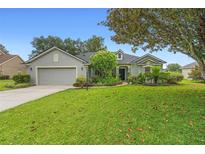 Charming one-story home featuring a well-manicured lawn, lush landscaping, and a two-car garage at 23510 Oak Prairie Cir, Sorrento, FL 32776