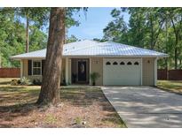 Charming single-story home with a light beige exterior, a white metal roof, and a well-maintained front lawn at 3005 Se 156Th Place Rd, Summerfield, FL 34491