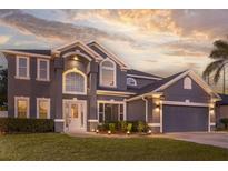 Stunning two-story home with a well-manicured lawn and an elegant entrance, set against a backdrop of a beautiful sunset at 1157 Hollow Pine Dr, Oviedo, FL 32765