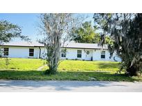 Charming single-story home with white exterior, well-manicured lawn, and mature trees at 251 Celery Cir, Oviedo, FL 32765