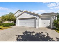 Exterior of a charming home showcasing a three-car garage and well-maintained landscaping at 2297 Montbrook Pl, The Villages, FL 32162