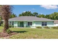 Charming single-story home featuring a well-maintained lawn, mature trees, and a lovely light green exterior at 3968 Sw 131St Place Rd, Ocala, FL 34473
