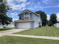 Charming two-story home featuring a 2-car garage, manicured lawn, and a large arched window providing tons of natural light at 2233 Ardon Ave, Orlando, FL 32833