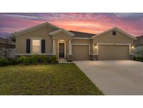 Inviting single-Gathering home with a well-manicured lawn and a two-car garage, showcasing charming exterior details under a vibrant sky at 8123 Sw 57Th Ct, Ocala, FL 34476