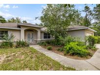 Charming single-story home featuring a well-manicured lawn and inviting front entrance with decorative glass door at 9879 Sw 38Th Ave, Ocala, FL 34476