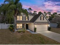 Charming two-story home with tan siding, brick accents, and a well-manicured lawn at dusk at 1029 Evans Loop, Lake Wales, FL 33853