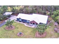 Stunning aerial view of a home with a metal roof, lush landscaping, and a covered parking area at 112 Reedy Creek Dr, Frostproof, FL 33843