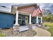 Front porch with stone columns, American flag and rocking chairs at 112 Reedy Creek Dr, Frostproof, FL 33843