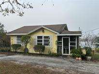 Yellow house with a screened porch and landscaped yard at 1120 S Scenic Hwy, Lake Wales, FL 33853