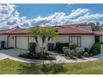 Charming home featuring a red tile roof, mature landscaping, and an attached two-car garage at 2680 Clubhouse Dr, Lake Wales, FL 33898