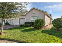 Tan house with two-car garage, landscaped lawn, and brick walkway at 3020 Caneel St, Winter Haven, FL 33884