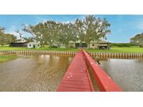 View down red wooden dock of waterfront home with green roof, backyard, and canal views at 1301 S Lake Reedy Blvd, Frostproof, FL 33843