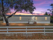 Charming single-story home featuring a metal roof and white picket fence at sunset at 2391 Buck Board Trl, Lake Wales, FL 33898