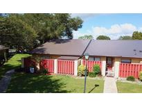 Inviting home featuring a metal roof, well-maintained lawn and a charming red fence for added privacy at 1077 Medinah Way, Winter Haven, FL 33884