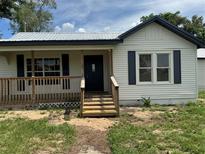Charming exterior view features a front porch with wooden steps and railings and a freshly painted facade at 111 D St, Frostproof, FL 33843