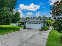 Charming single-story home featuring a well-manicured lawn, mature trees, and a two-car garage on a sunny day at 1144 Cephia St, Lake Wales, FL 33853