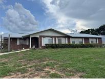 Charming brick home featuring a metal roof, neat landscaping, and a welcoming front porch at 400 W 4Th Ct, Frostproof, FL 33843