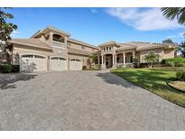 Elegant home featuring a paver driveway, three-car garage, and covered entryway with decorative columns at 6487 Ashley Dr, Lakeland, FL 33813