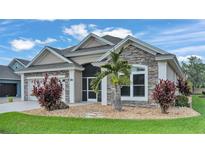 Charming home exterior with stone accents, lush landscaping, and a well-manicured lawn, creating a welcoming curb appeal at 8288 Lake James Dr, Lakeland, FL 33810