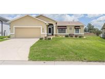 Inviting front yard with well-manicured lawn and neutral-toned single-Gathering home with a tan driveway at 5879 Swallow Dr, Lakeland, FL 33809