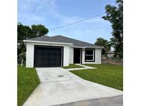 Charming single-story home with a well-manicured lawn and black garage door at 1918 Dr Martin L King Jr Way, Haines City, FL 33844