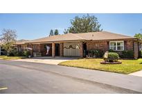 Charming single-story brick home with a covered carport, patriotic decorations, and well-maintained landscaping at 480 Nighthawk Dr, Lakeland, FL 33813