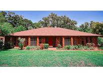 Charming brick home featuring a red door and manicured landscaping at 4428 Sugartree E Dr, Lakeland, FL 33813