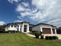 Beautiful single-story home featuring manicured lawn, an arched entryway, and a three-car garage at 5074 Shore Side Dr, Lakeland, FL 33812