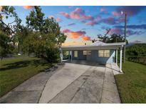 Charming single-story home with a covered parking area and a well-manicured front yard with a beautiful sky at dusk at 1220 Woodland Ave, Lakeland, FL 33801