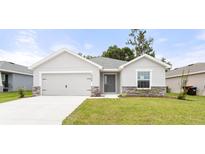 Charming single-story home features a well-manicured lawn, stone accents, and a two-car garage at 5335 Se 127Th Ln, Belleview, FL 34420