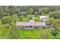 Expansive property featuring a brick home, large lawn, detached garage, and picturesque pond at 9240 Moore Rd, Lakeland, FL 33809