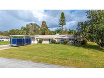 Charming single-story home featuring a spacious front yard and attached carport at 6029 Avocado Dr, Indian Lake Estates, FL 33855