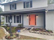Two-story house with gray painted brick, a coral door and landscaping at 1305 Avenue S Nw, Winter Haven, FL 33881