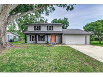 Charming two-story home featuring a well-manicured lawn, light gray paint, brick accents, and a driveway leading to a two-car garage at 1305 Avenue S Nw, Winter Haven, FL 33881