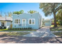 Charming single-story home with blue exterior, manicured lawn, and brick paved driveway leading to a covered carport at 311 E Belmar St, Lakeland, FL 33803