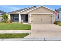 Tan one-story house with a two-car garage and nicely landscaped lawn at 1034 Corso Dr, Winter Haven, FL 33884