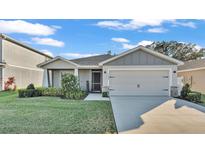 Charming one-story home with gray siding, a two-car garage, and a well-manicured lawn at 1299 Mezzavalle Way, Auburndale, FL 33823