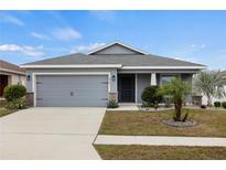 Gray house with two-car garage and landscaped front yard at 416 Monticelli Dr, Haines City, FL 33844
