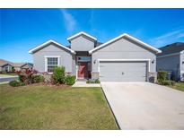 Gray house with red door, two-car garage, and landscaped lawn at 4340 Reding Way, Lakeland, FL 33813