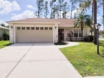 Beige house with two-car garage, landscaped lawn, and palm trees at 8052 Sugar Pine Blvd, Lakeland, FL 33810
