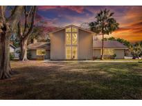 Two-story house with a large yard, mature trees, and a sunset backdrop at 1118 Cypress W Pt, Winter Haven, FL 33884