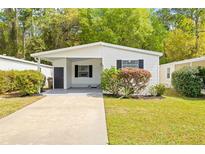 White single-wide manufactured home with carport, landscaping, and paved driveway at 32334 Oak Park Dr, Leesburg, FL 34748