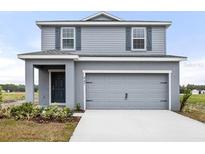 Charming two-story home with gray siding and a two-car garage, showcasing modern curb appeal at 447 Ituna Cir, Winter Haven, FL 33881
