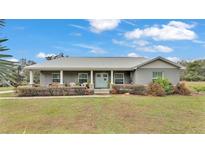 House exterior features a gray metal roof, light gray siding, and a stone accented front porch at 5576 Albert Williams Rd, Mulberry, FL 33860