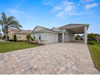 Single-story home with light-colored siding, paver driveway, and landscaping at 715 Teaberry Trl, Polk City, FL 33868