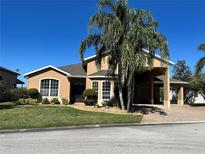Charming single-story home with lush landscaping, large palm tree, and a spacious driveway at 1015 Crossroads Dr, Polk City, FL 33868