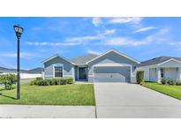 Charming single-story home with a well-manicured lawn and a two-car garage on a sunny day at 1342 Mezzavalle Way, Auburndale, FL 33823