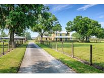Long driveway leading to a yellow farmhouse with large trees and fenced pastures at 1722 Broken Arrow N Trl, Lakeland, FL 33813