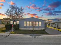 Mobile home exterior at sunset, featuring a carport and well-maintained landscaping at 2206 Golden Horseshoe N Cir, Lakeland, FL 33810