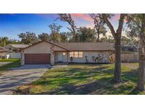 Updated single-story home with a brown garage door and stone accents at 7801 Rolling Grove W Dr, Lakeland, FL 33810